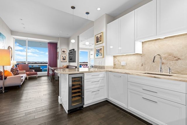 a kitchen with stainless steel appliances kitchen island granite countertop a table chairs in it and wooden floors