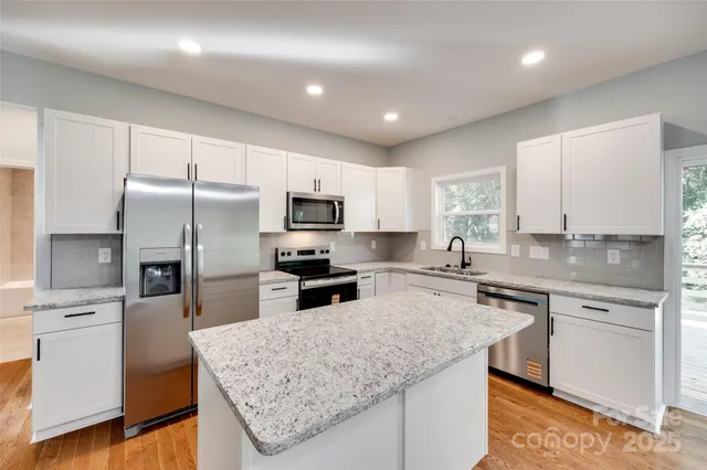 a kitchen with stainless steel appliances granite countertop a sink stove microwave and refrigerator