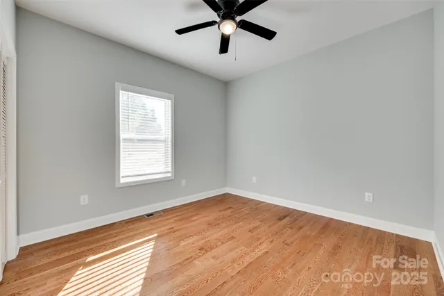 an empty room with a window and a fan