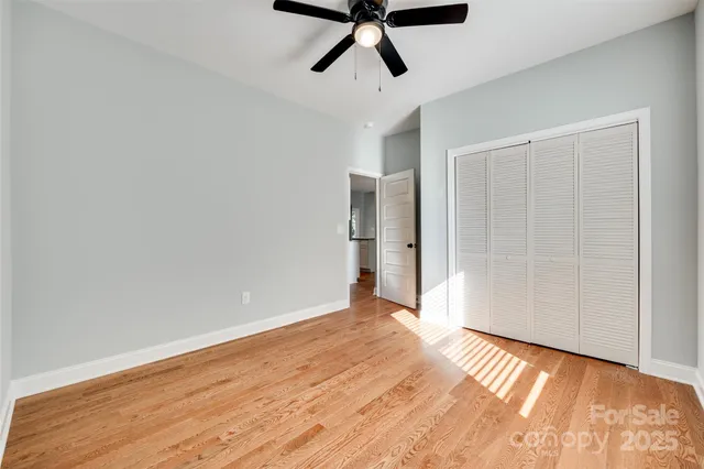 a view of empty room with wooden floor and ceiling fan
