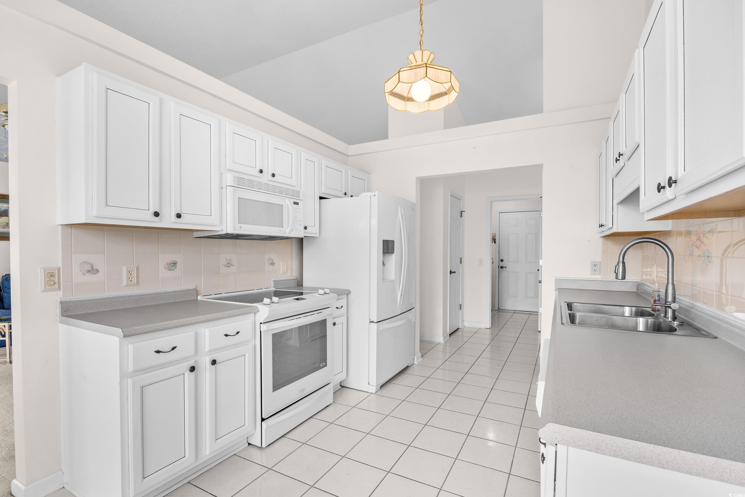 1744 Starbridge Drive Surfside Beach, SC 29575 - Photo 11 of 38 Kitchen featuring backsplash, white appliances, white cabinets, light countertops, and vaulted ceiling