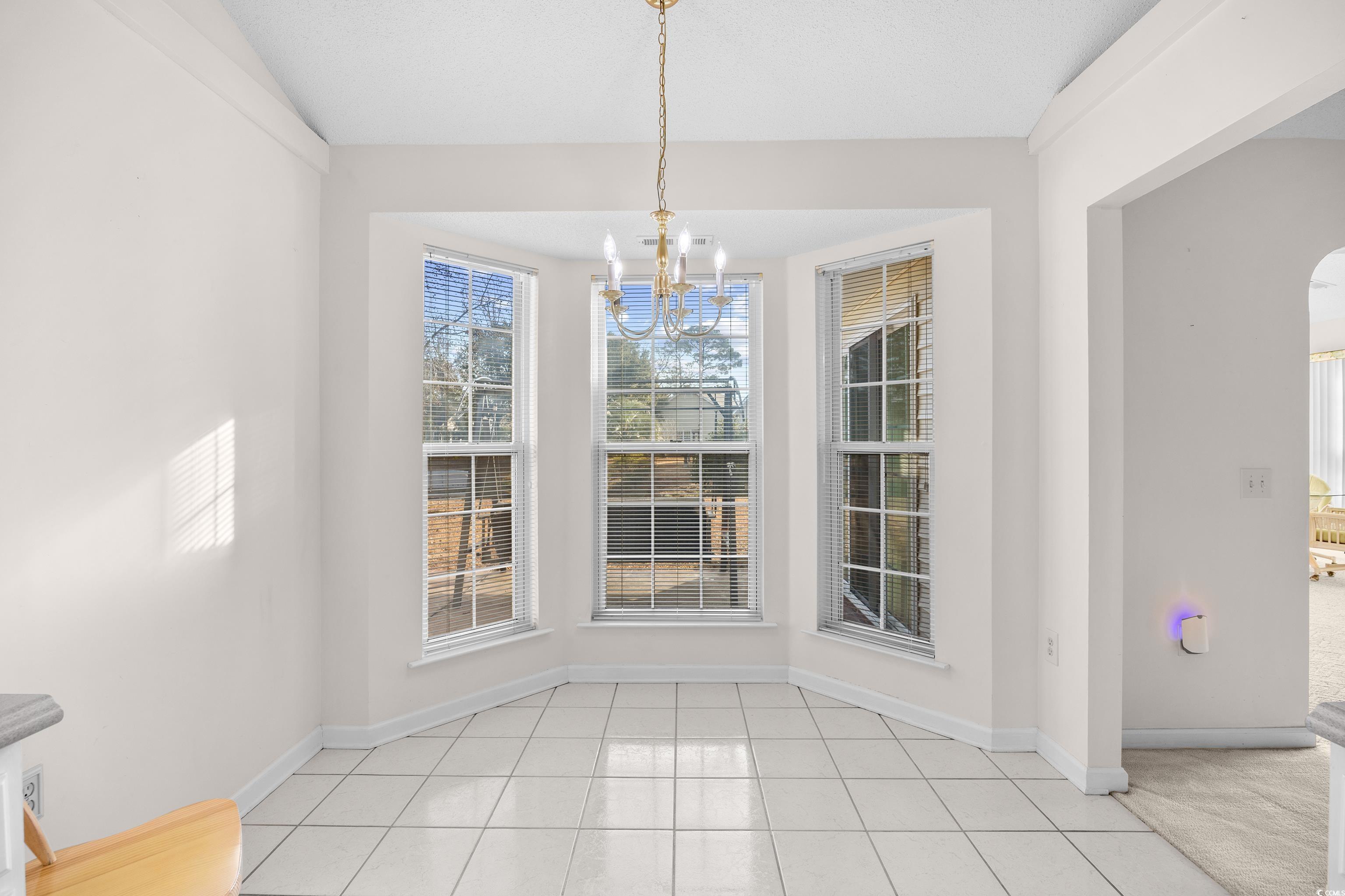 1744 Starbridge Drive Surfside Beach, SC 29575 - Photo 13 of 38 Unfurnished dining area featuring a chandelier, arched walkways, and light tile patterned floors