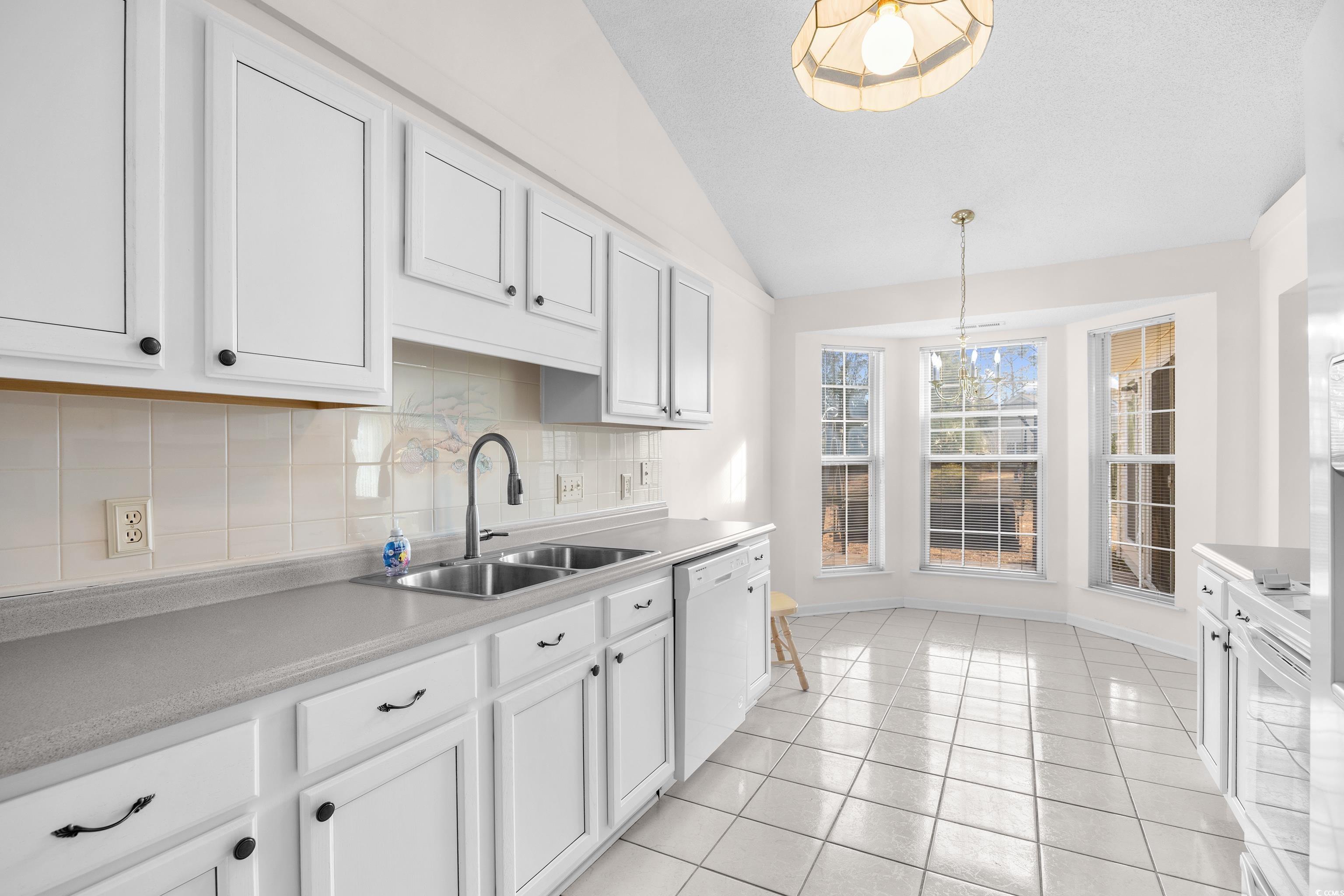 1744 Starbridge Drive Surfside Beach, SC 29575 - Photo 14 of 38 Kitchen with vaulted ceiling, decorative backsplash, white cabinetry, and white appliances