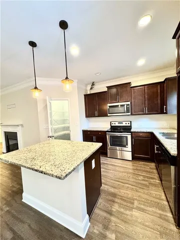 a kitchen with kitchen island granite countertop stainless steel appliances and wooden cabinets