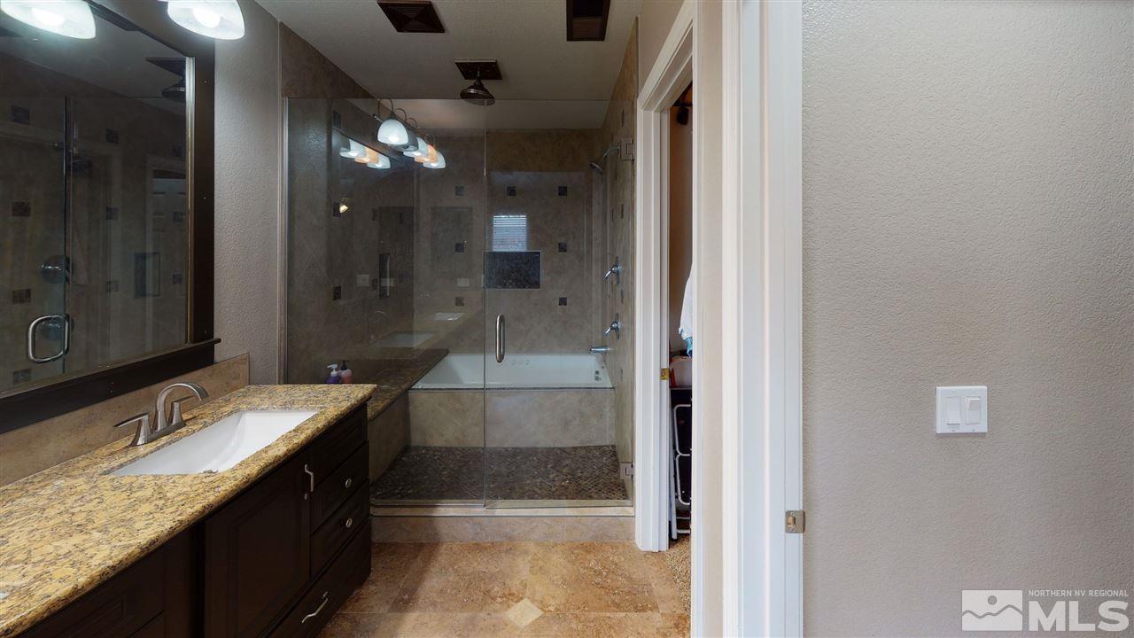 8900 Griffon Court Reno, NV 89506 - Photo 8 of 29 a bathroom with a granite countertop sink a mirror and a shower