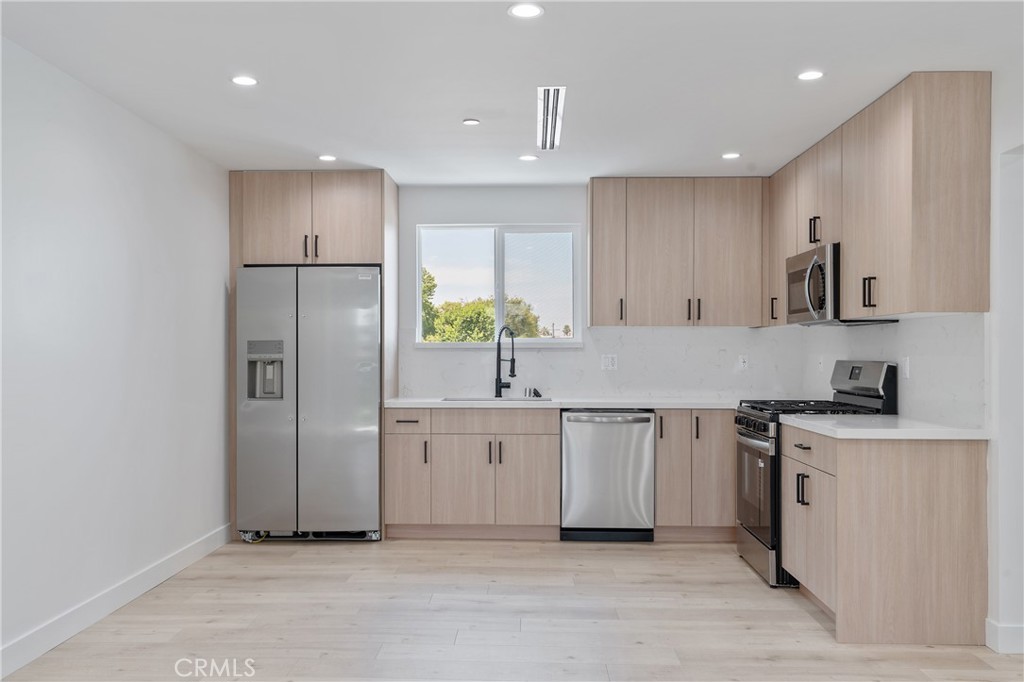 7435 Ranchito Avenue Van Nuys, CA 91405 - Photo 3 of 16 a kitchen with stainless steel appliances a refrigerator sink and white cabinets
