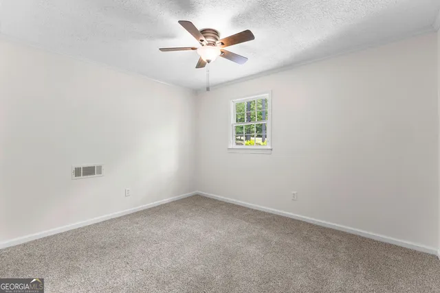 an empty room with a window and a ceiling fan