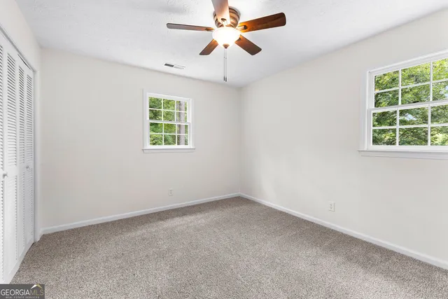 an empty room with a window and a fan