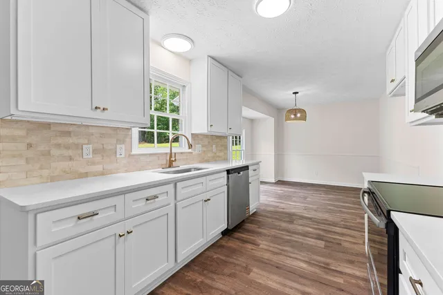 a kitchen with granite countertop white cabinets and a wooden floor