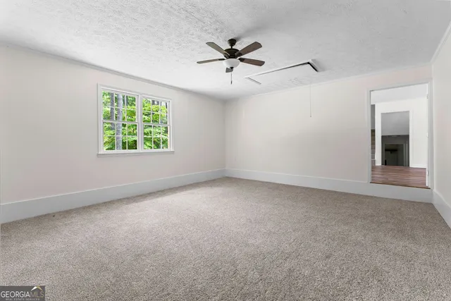 an empty room with windows and ceiling fan