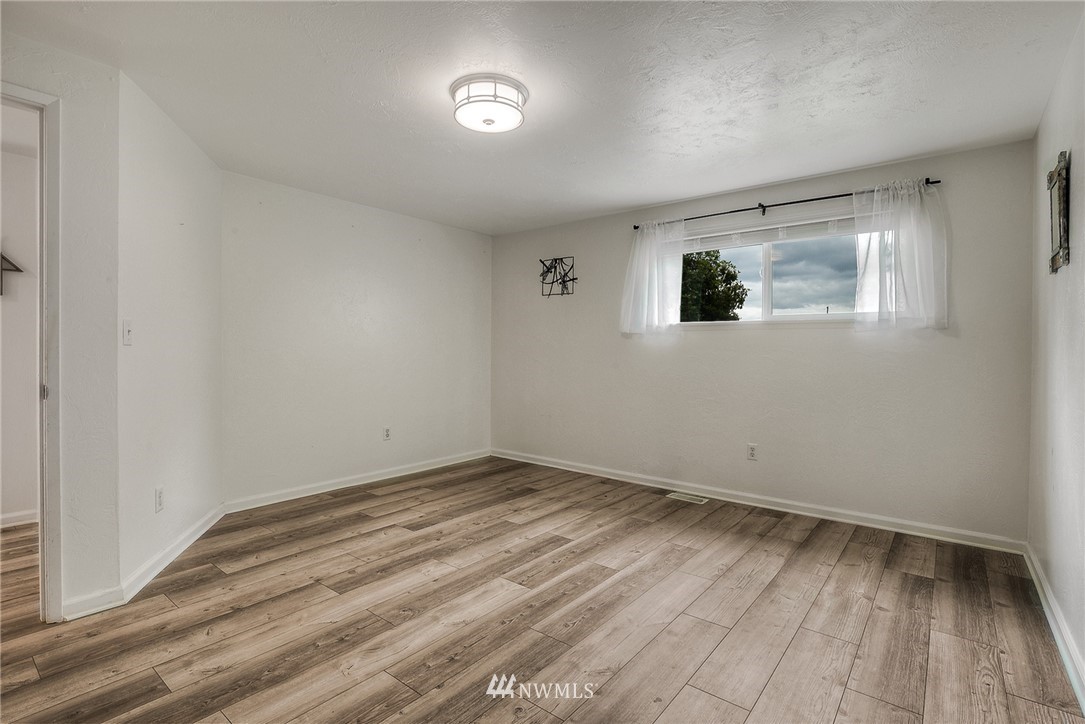 7484 Riverside Drive East Sumner, WA 98390 - Photo 14 of 23 an empty room with wooden floor and windows