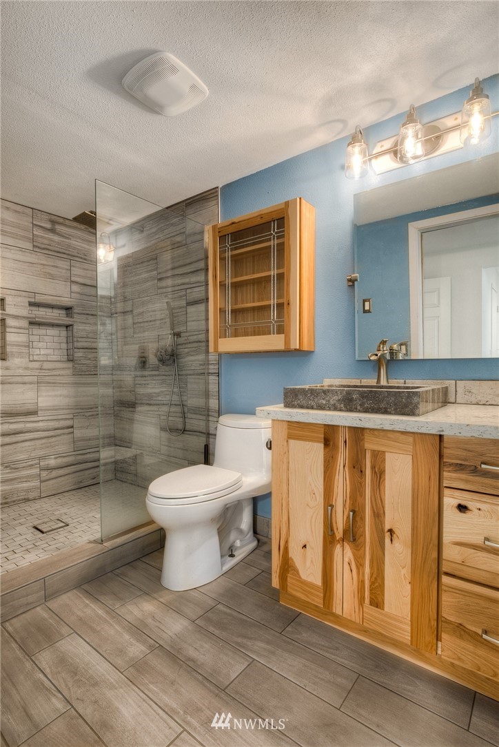 7484 Riverside Drive East Sumner, WA 98390 - Photo 10 of 23 a bathroom with a granite countertop sink toilet a mirror and shower