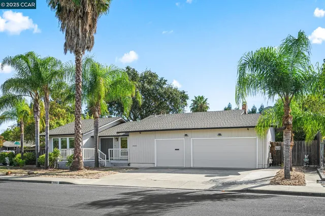 a front view of a house with a yard and palm trees