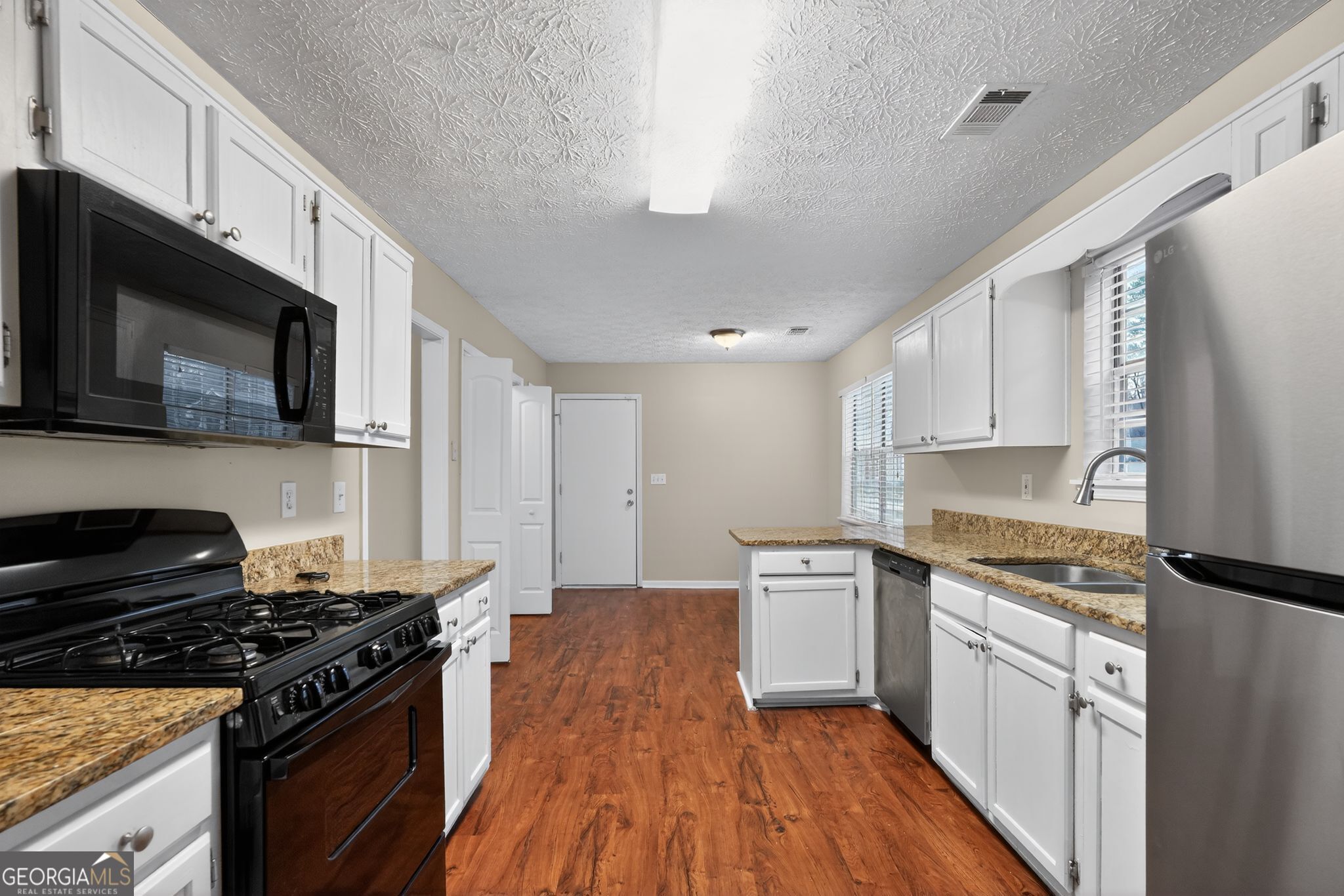 205 Whirlwind Court Atlanta, GA 30349 - Photo 12 of 32 a kitchen with a stove a sink and a microwave