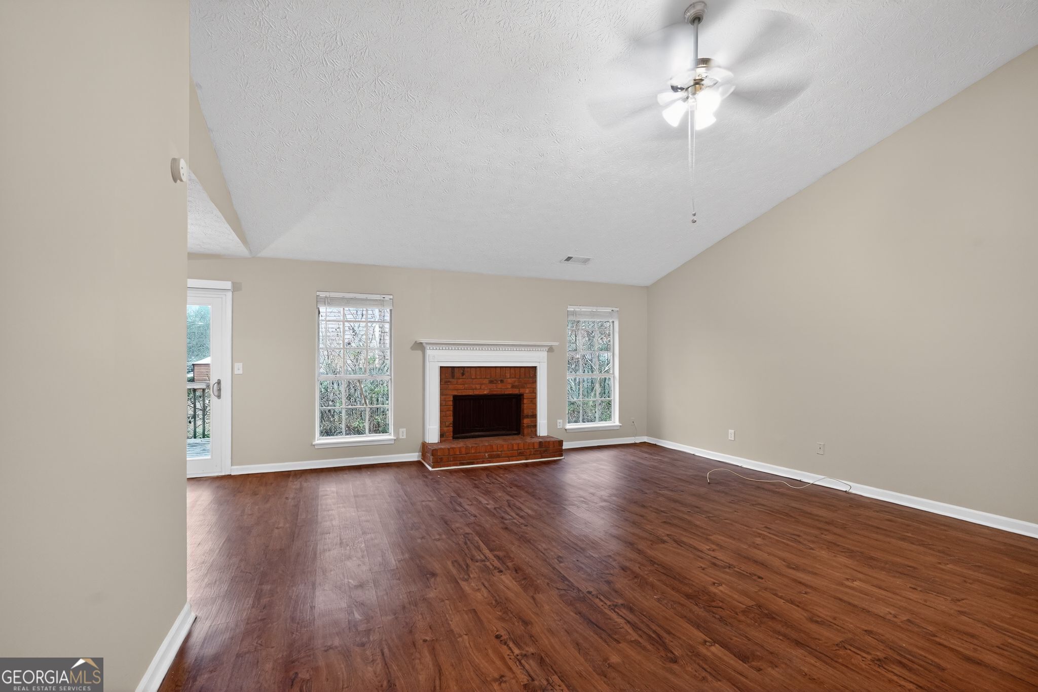 205 Whirlwind Court Atlanta, GA 30349 - Photo 7 of 32 an empty room with wooden floor fireplace and windows
