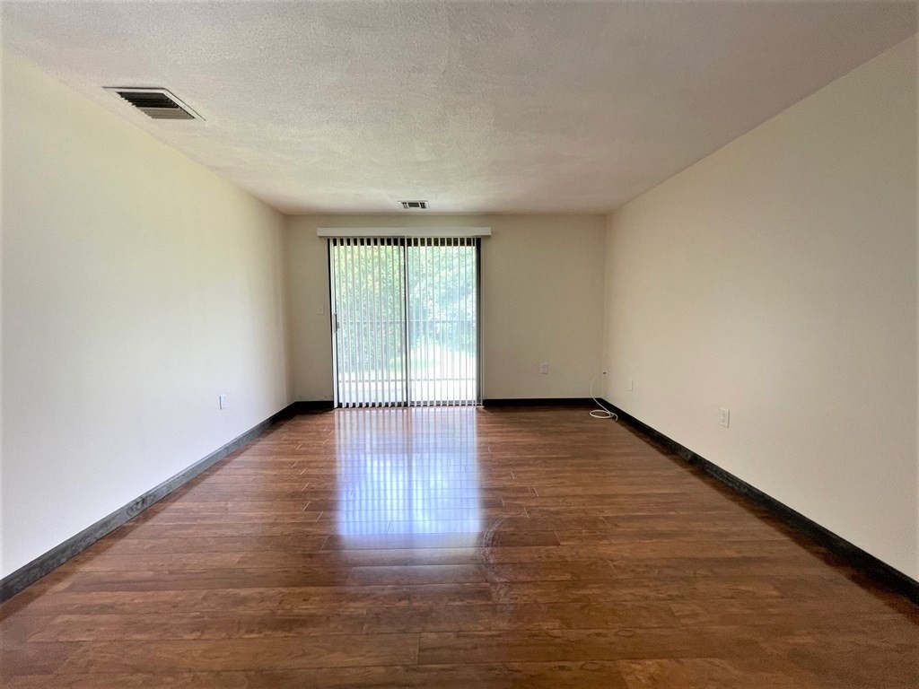 555 Main Street, Unit 202 Stoneham, MA 02180 - Photo 3 of 8 a view of an empty room with wooden floor and a window