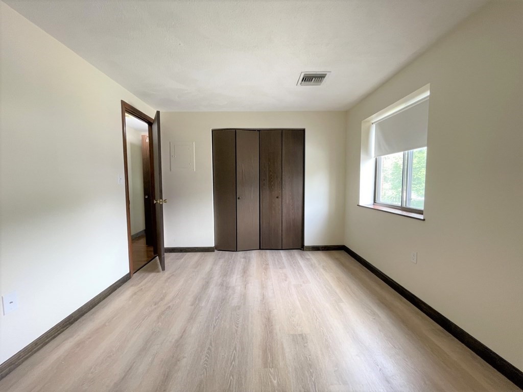 555 Main Street, Unit 202 Stoneham, MA 02180 - Photo 4 of 8 an empty room with wooden floor and windows