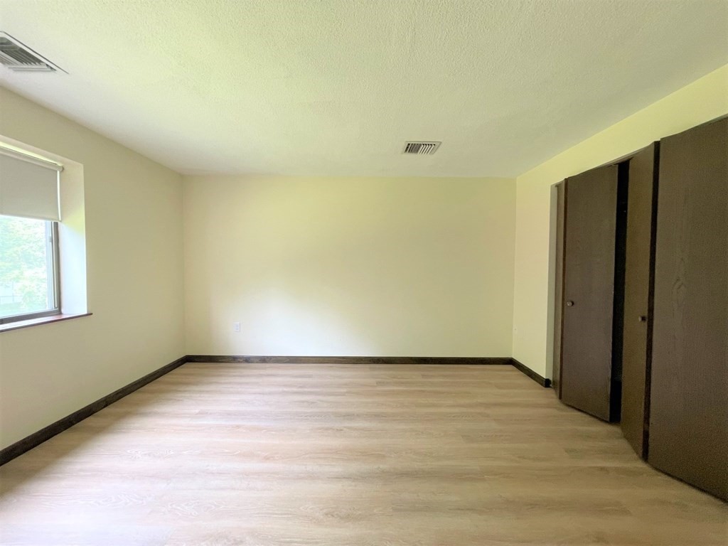 555 Main Street, Unit 202 Stoneham, MA 02180 - Photo 5 of 8 a view of an empty room with wooden floor and a window