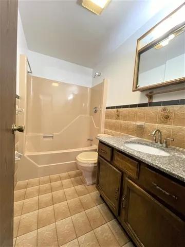 a bathroom with a granite countertop sink a toilet a mirror and shower