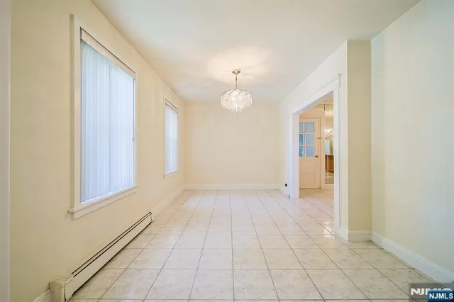 a view of an empty room with window and chandelier fan