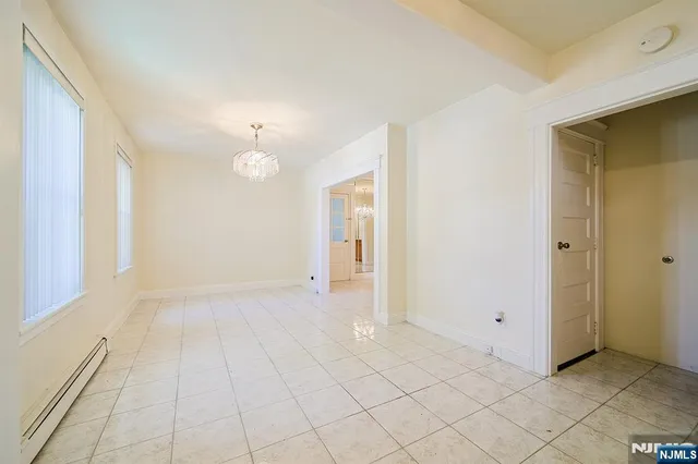 a view of an empty room with window and chandelier fan