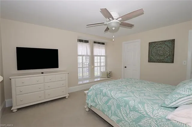a bedroom with a large bed a flat screen tv on dresser and a window