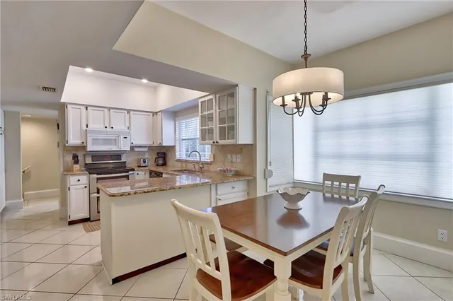 a kitchen with stainless steel appliances granite countertop a sink a stove a dining table and chairs