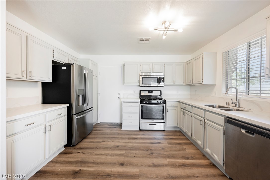 112 Iridescent Street Henderson, NV 89012 - Photo 1 of 24 A well-equipped kitchen features sleek stainless steel appliances, ample white cabinetry, and durable wood-look flooring.