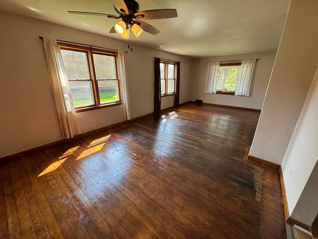 a view of an empty room with window and wooden floor