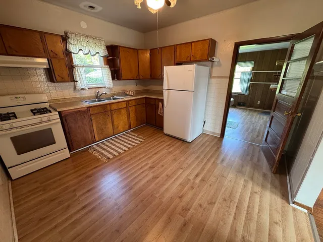 a kitchen with sink a refrigerator and wooden floor