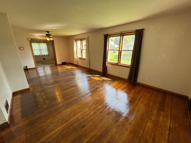 a view of empty room with wooden floor and fan