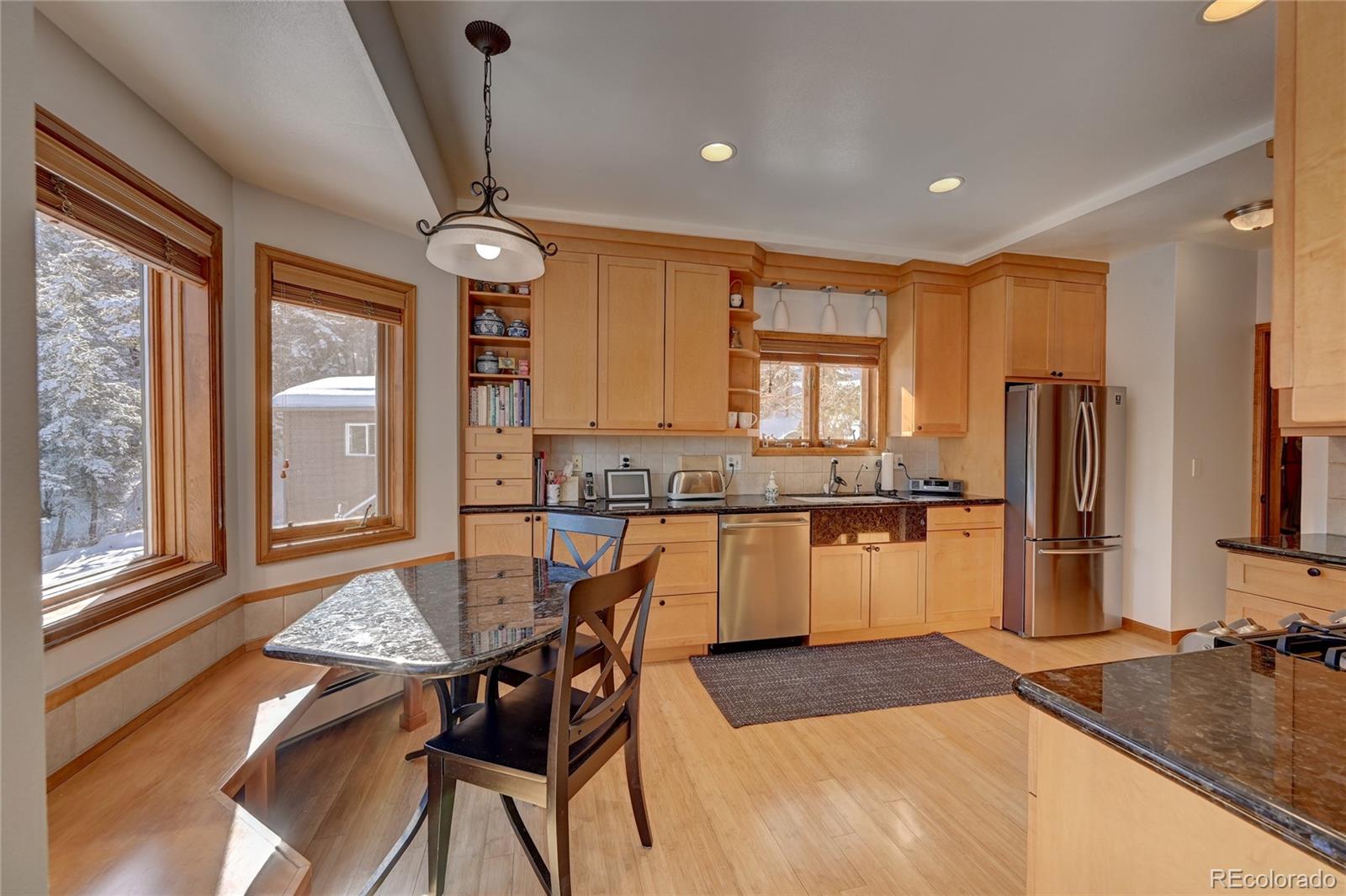 27 Conifer Road Golden, CO 80401 - Photo 11 of 40 a kitchen with stainless steel appliances granite countertop a stove top oven a sink a dining table and chairs with wooden floor