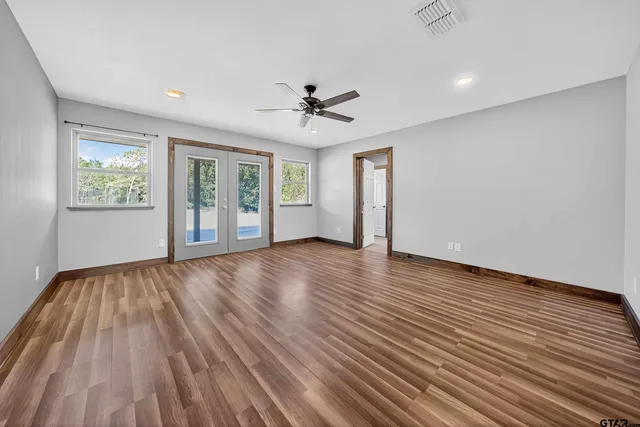 an empty room with wooden floor and windows