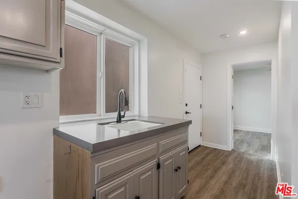 an empty room with wooden floor cabinet and windows