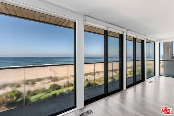 a view of an empty room with wooden floor and a fireplace
