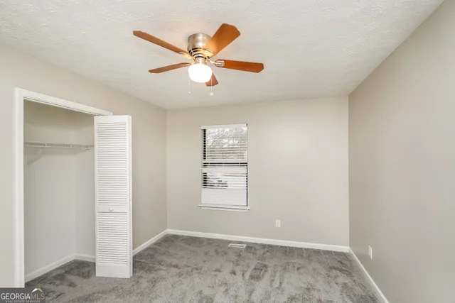 an empty room with windows and fan