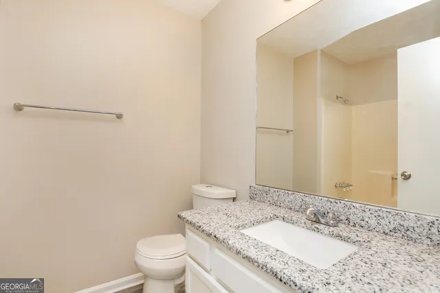 a bathroom with a granite countertop sink a toilet and a mirror