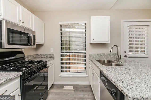 a kitchen with granite countertop a sink stove and cabinets