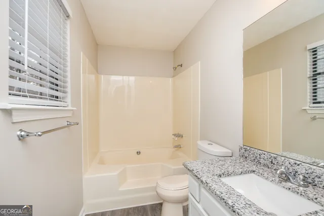 a bathroom with a granite countertop sink a toilet and shower