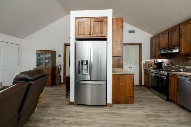 a kitchen with granite countertop stainless steel appliances a refrigerator a stove a cabinets and a refrigerator