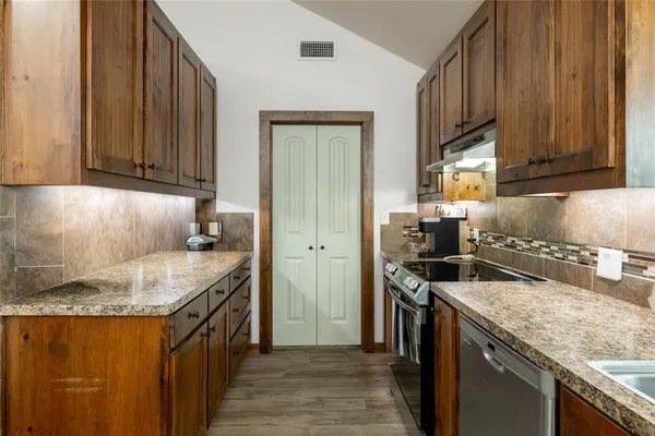 a kitchen with granite countertop a sink stove and cabinets