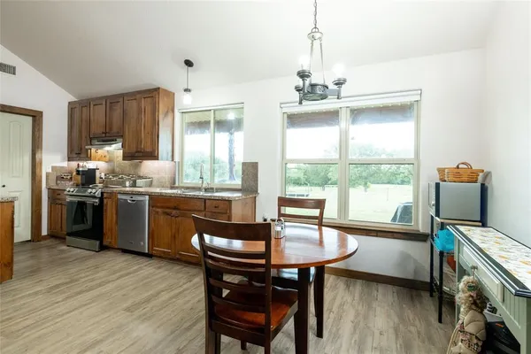 a kitchen with a table chairs a sink dishwasher window and cabinets