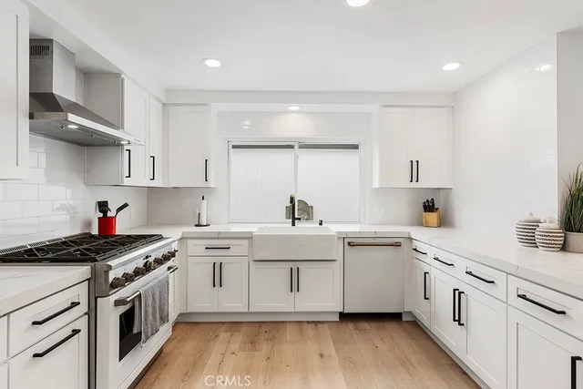 a large white kitchen with stainless steel appliances granite countertop a sink and cabinets