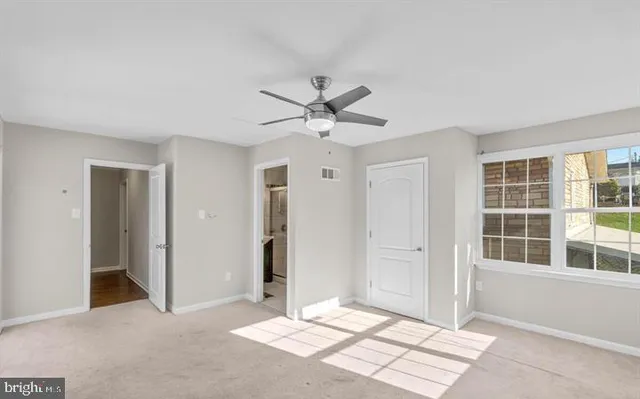 an empty room with chandelier fan and windows