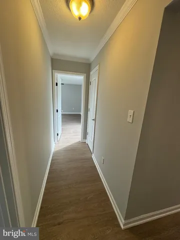 a view of a hallway with wooden floor and a bathroom