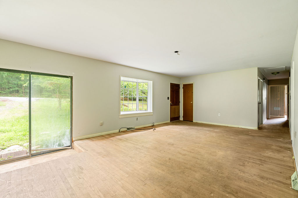 712 Whitney Way Anderson, SC 29625 - Photo 13 of 31 Natural light cascades through broad windows and a sliding glass door, illuminating the durable wood flooring.