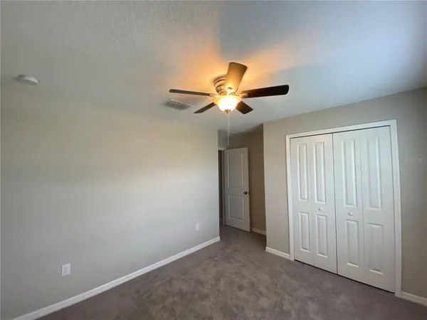 an empty room with closet and a chandelier fan