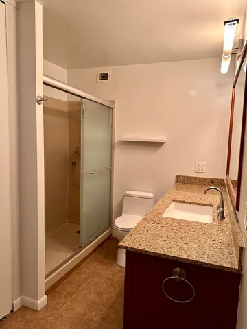a bathroom with a granite countertop sink a toilet and shower