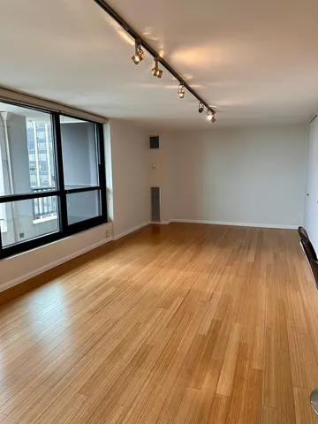 a view of empty room with wooden floor and fan