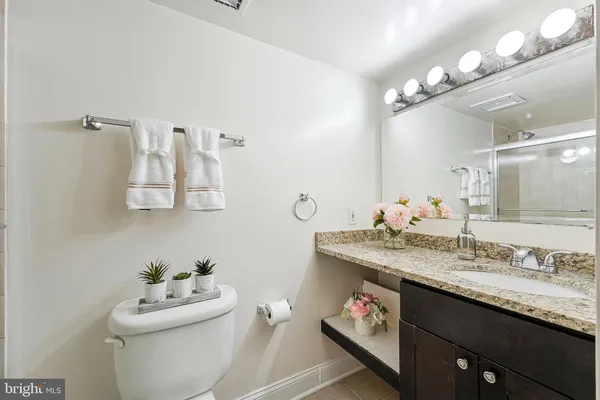 a bathroom with a granite countertop sink a toilet and a mirror